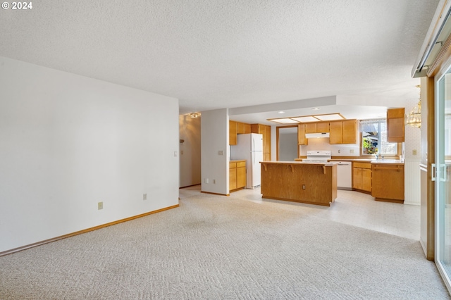 interior space featuring white appliances, sink, light colored carpet, a kitchen island, and a textured ceiling