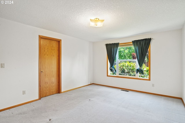 spare room featuring light carpet and a textured ceiling