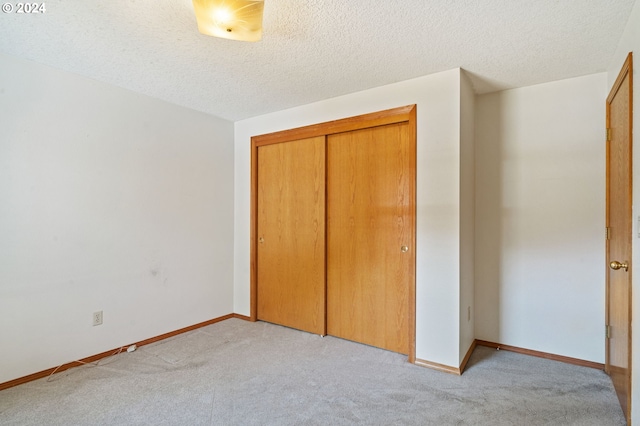 unfurnished bedroom with light carpet, a closet, and a textured ceiling