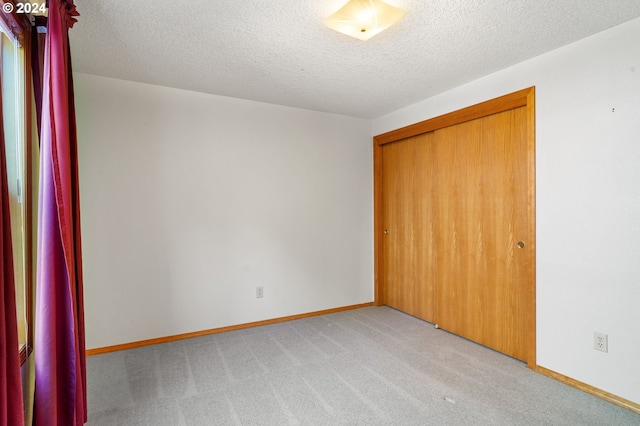 unfurnished bedroom featuring carpet, a textured ceiling, and a closet