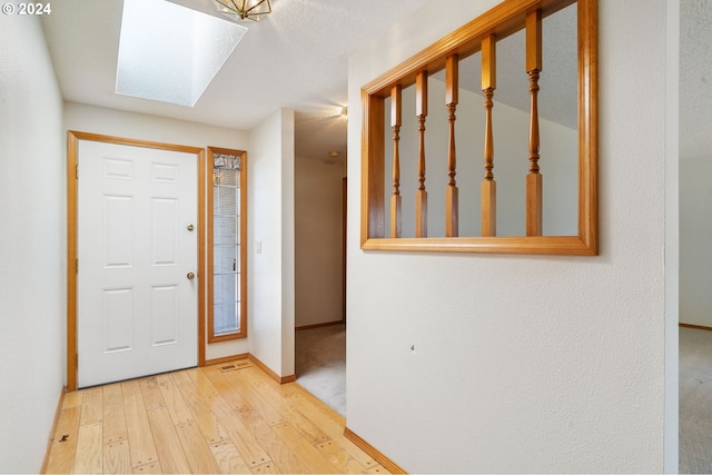 entrance foyer featuring a skylight and light colored carpet