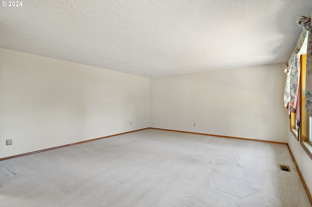 empty room with light carpet and a textured ceiling