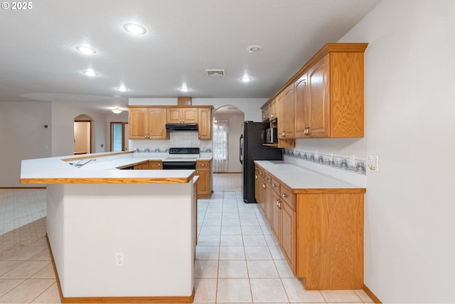 kitchen featuring black fridge, range with electric cooktop, decorative backsplash, light tile patterned flooring, and kitchen peninsula