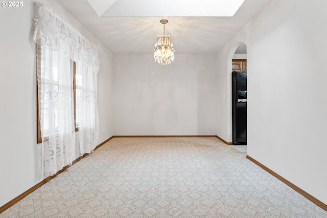 carpeted spare room featuring an inviting chandelier