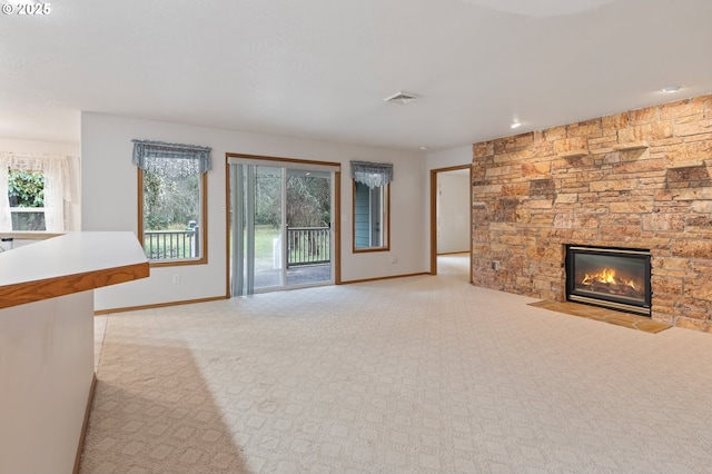 unfurnished living room featuring a stone fireplace and light colored carpet