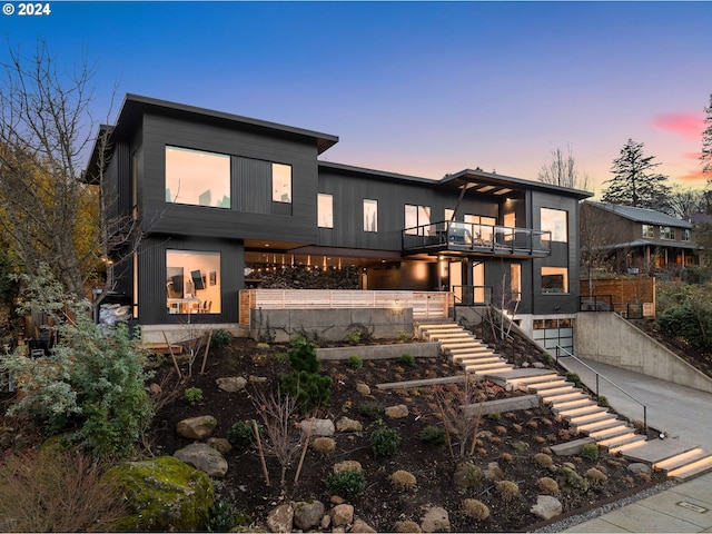 back house at dusk featuring a balcony