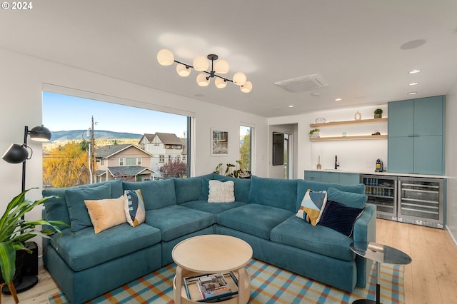 living room featuring a mountain view, wine cooler, a chandelier, and light hardwood / wood-style flooring