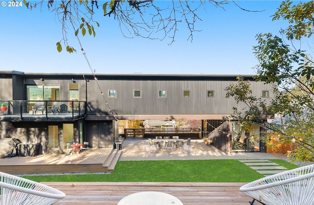 rear view of house featuring a deck, a patio area, and a lawn