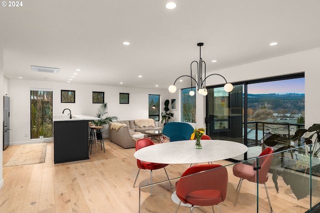 dining room featuring an inviting chandelier, sink, and light wood-type flooring