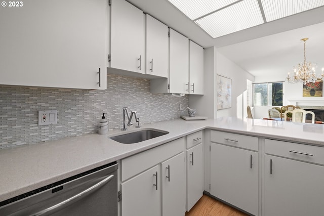 kitchen with light hardwood / wood-style flooring, backsplash, dishwasher, decorative light fixtures, and a notable chandelier