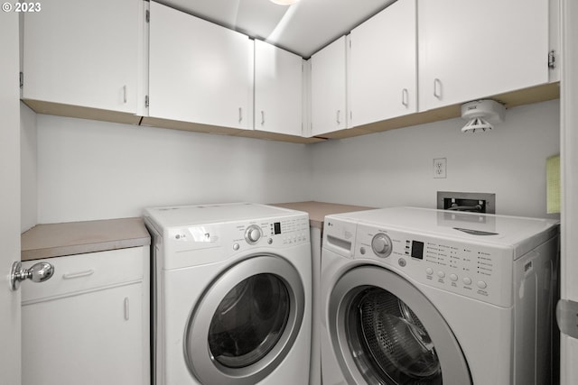 washroom with washer hookup, washing machine and dryer, and cabinets