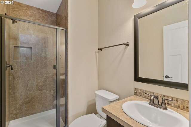 bathroom featuring vanity, backsplash, toilet, and an enclosed shower