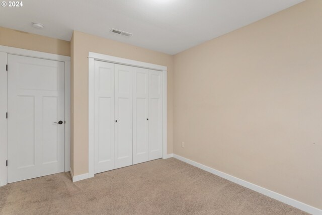 unfurnished bedroom featuring light carpet and a closet