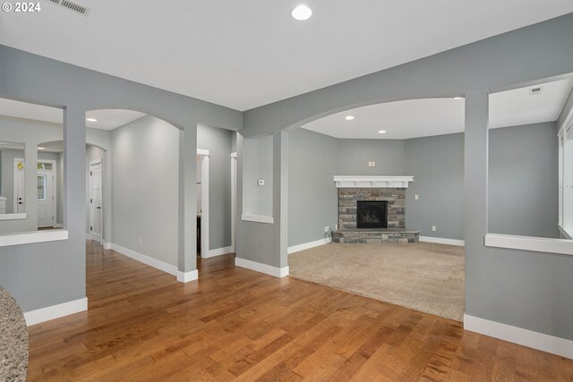 unfurnished living room featuring a stone fireplace and hardwood / wood-style floors