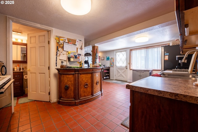 93777 Green Acres Ln, Coos Bay, OR 97420 - kitchen with dark tile patterned floors, a textured ceiling, dark countertops, and stove