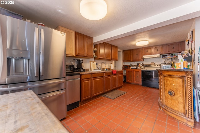 93777 Green Acres Ln, Coos Bay, OR 97420 - kitchen with stainless steel appliances, brown cabinets, under cabinet range hood, light tile patterned flooring, and a textured ceiling