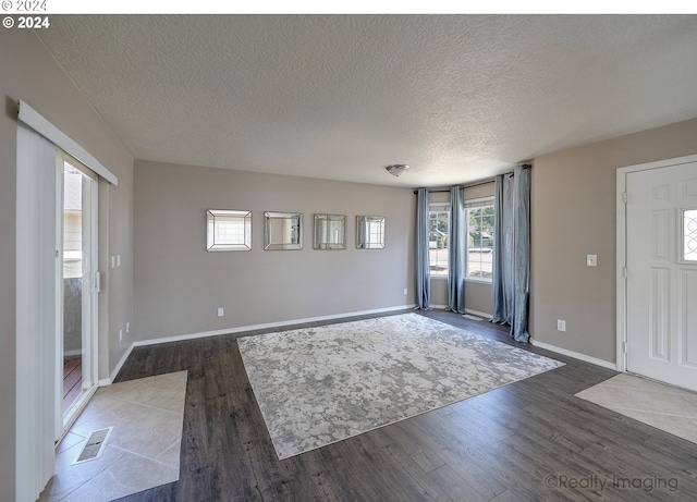 unfurnished living room with hardwood / wood-style flooring and a textured ceiling