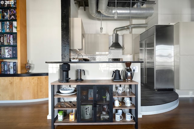 interior space with hardwood / wood-style flooring, tasteful backsplash, and wall chimney range hood