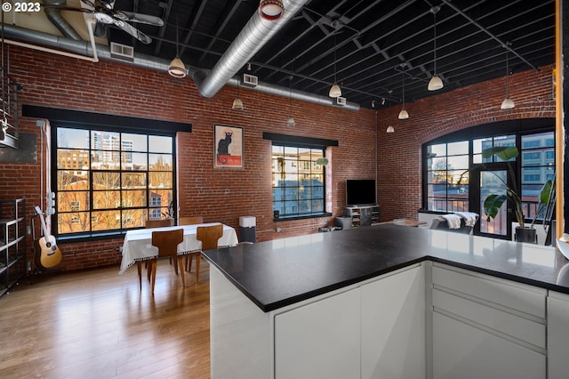 kitchen featuring white cabinets, brick wall, a wealth of natural light, and light hardwood / wood-style flooring