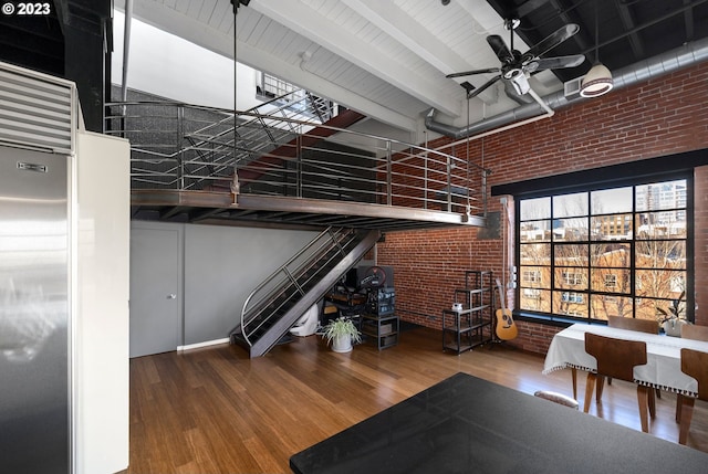 interior space with high quality fridge, ceiling fan, hardwood / wood-style floors, and brick wall