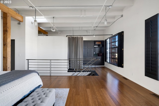 unfurnished bedroom featuring beam ceiling and dark hardwood / wood-style flooring