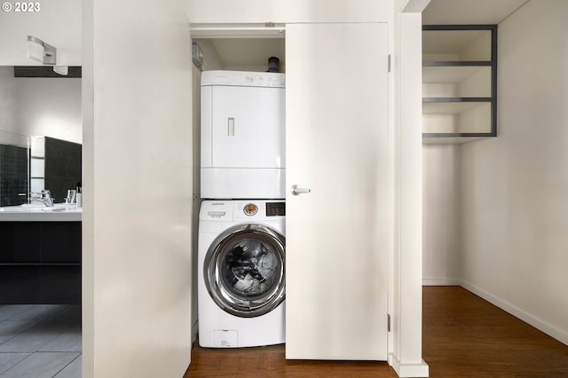 laundry area featuring hardwood / wood-style flooring, stacked washer / drying machine, and sink