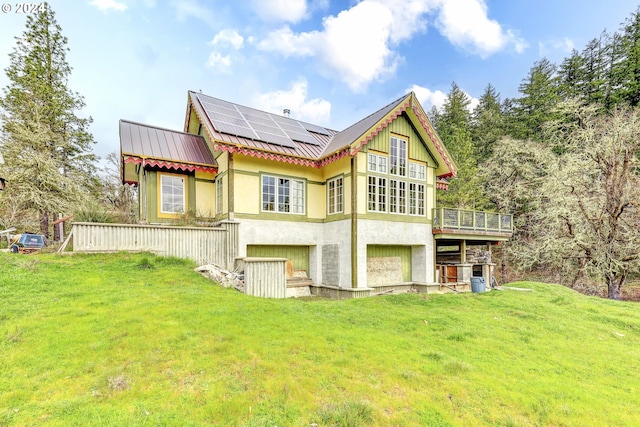 rear view of property featuring a garage, solar panels, metal roof, and stucco siding