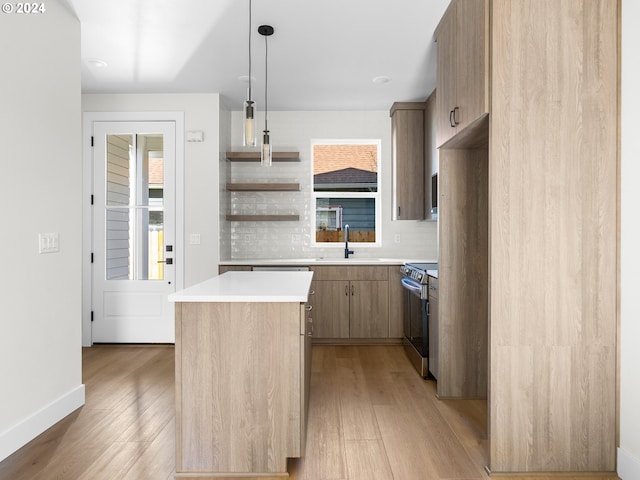 kitchen featuring light hardwood / wood-style floors, electric stove, a center island, decorative light fixtures, and sink