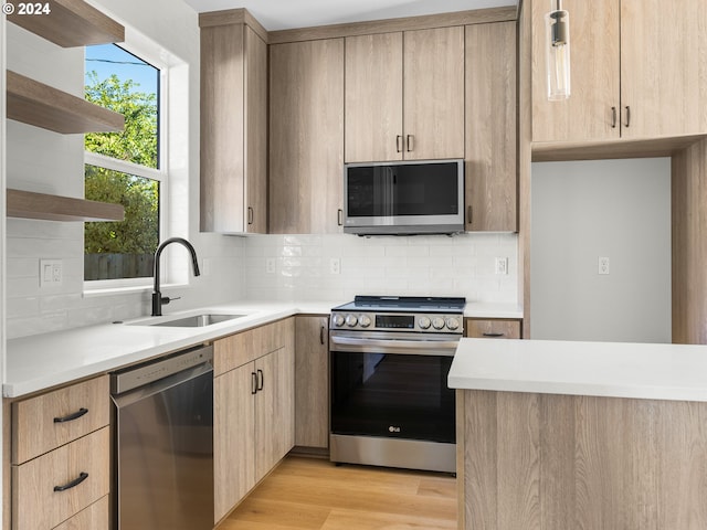 kitchen featuring sink, stainless steel appliances, light brown cabinetry, light hardwood / wood-style floors, and decorative backsplash