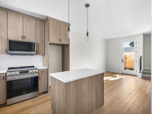 kitchen featuring tasteful backsplash, decorative light fixtures, stainless steel appliances, a center island, and light hardwood / wood-style floors