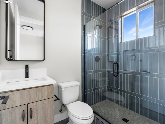 bathroom with a shower with shower door, vanity, and toilet