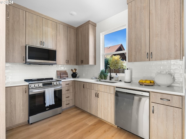 kitchen with light brown cabinets, stainless steel appliances, sink, and light hardwood / wood-style flooring