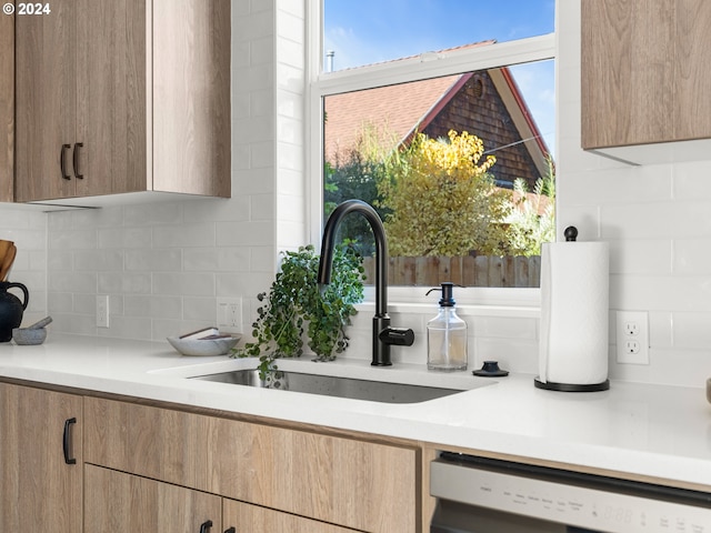 kitchen with backsplash, sink, and dishwashing machine