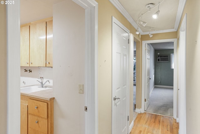 corridor with ornamental molding, sink, a wall unit AC, and light hardwood / wood-style flooring