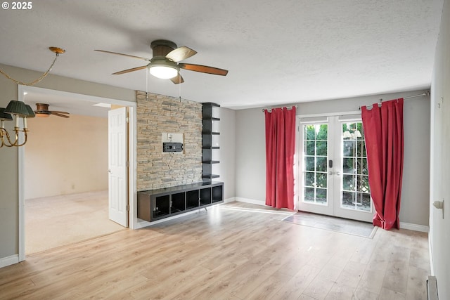 unfurnished living room featuring ceiling fan, french doors, a textured ceiling, and light wood-type flooring