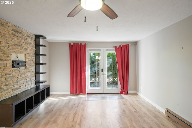 unfurnished living room featuring french doors, a baseboard heating unit, ceiling fan, a textured ceiling, and light hardwood / wood-style floors