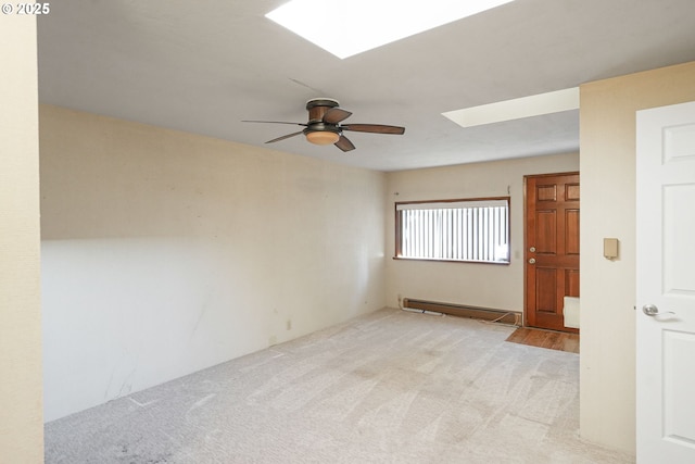 carpeted spare room with ceiling fan, baseboard heating, and a skylight