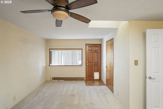 empty room featuring ceiling fan, light colored carpet, and a baseboard radiator