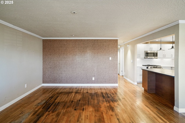 interior space with a textured ceiling, light hardwood / wood-style floors, and crown molding