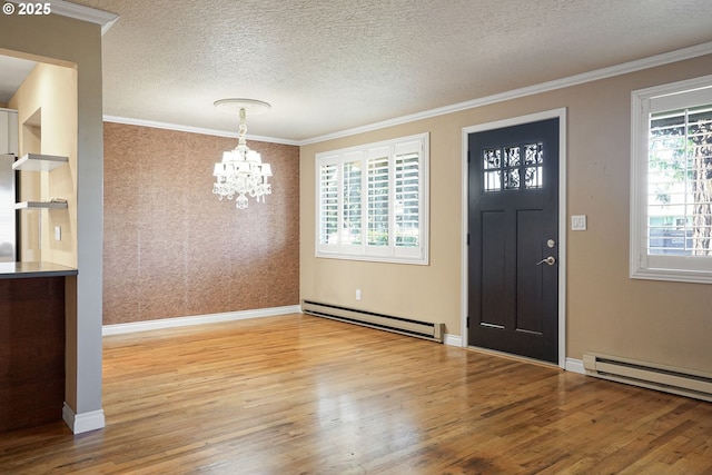 foyer with a wealth of natural light, a chandelier, light hardwood / wood-style flooring, and a baseboard radiator