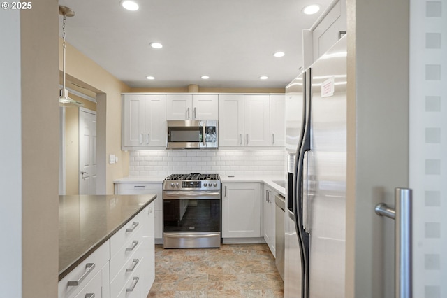 kitchen featuring dark stone counters, white cabinetry, hanging light fixtures, and stainless steel appliances