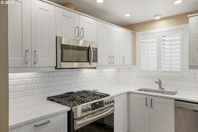 kitchen featuring tasteful backsplash, sink, white cabinets, and appliances with stainless steel finishes