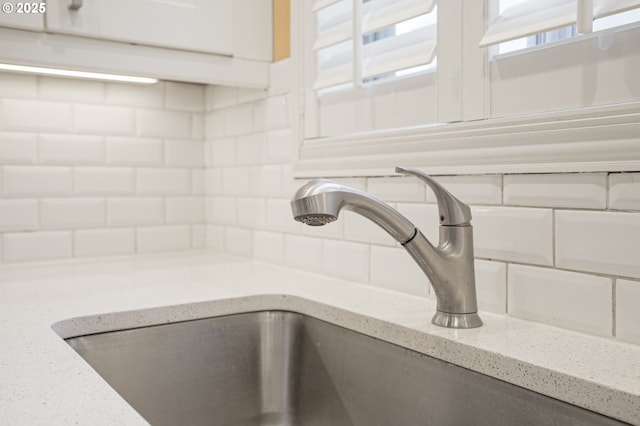 room details featuring tasteful backsplash, light stone counters, and sink