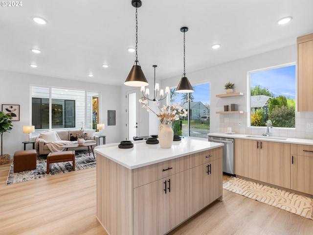 kitchen with sink, stainless steel dishwasher, a kitchen island, light brown cabinets, and light wood-type flooring