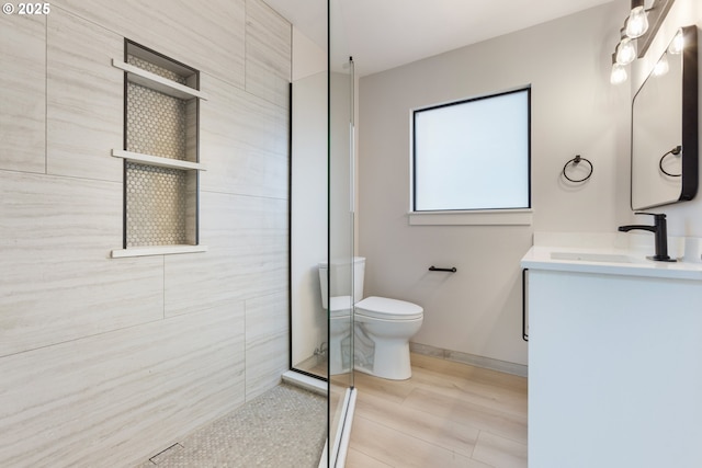 bathroom with wood-type flooring, vanity, a shower with shower door, and toilet