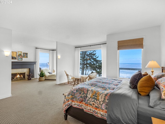 carpeted bedroom featuring a water view and a tiled fireplace