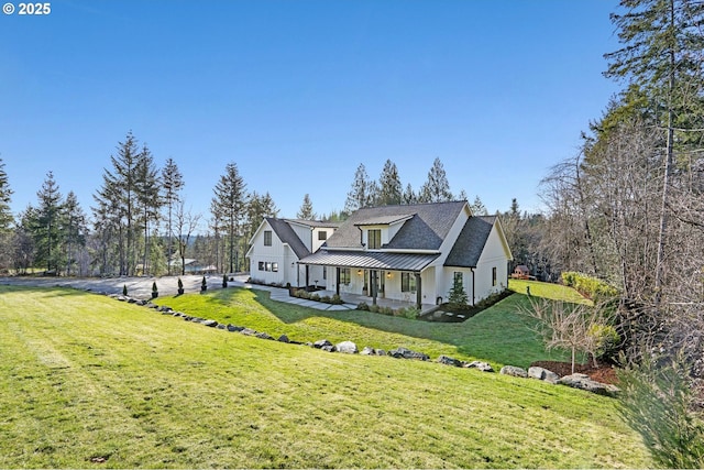 exterior space featuring covered porch, metal roof, a standing seam roof, and a front yard