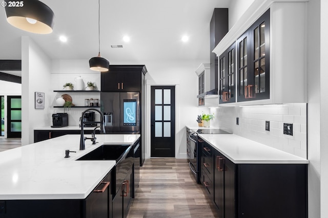 kitchen featuring light wood-style flooring, backsplash, stainless steel appliances, light countertops, and glass insert cabinets