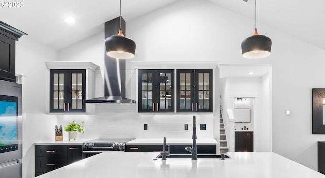 kitchen featuring backsplash, dark cabinetry, appliances with stainless steel finishes, wall chimney exhaust hood, and light countertops