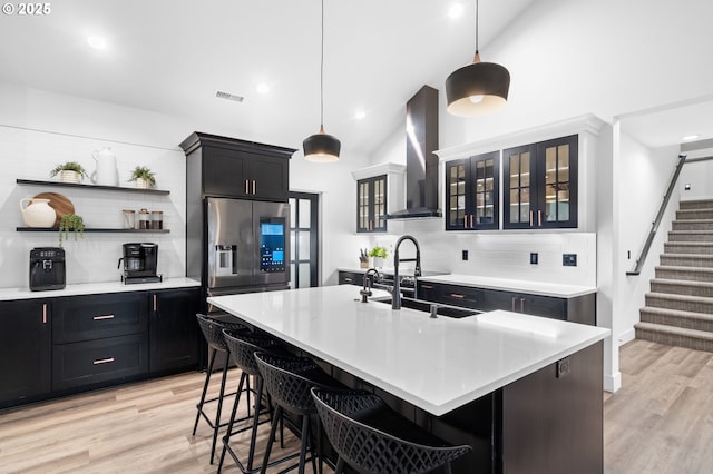 kitchen featuring visible vents, open shelves, a sink, light countertops, and wall chimney exhaust hood